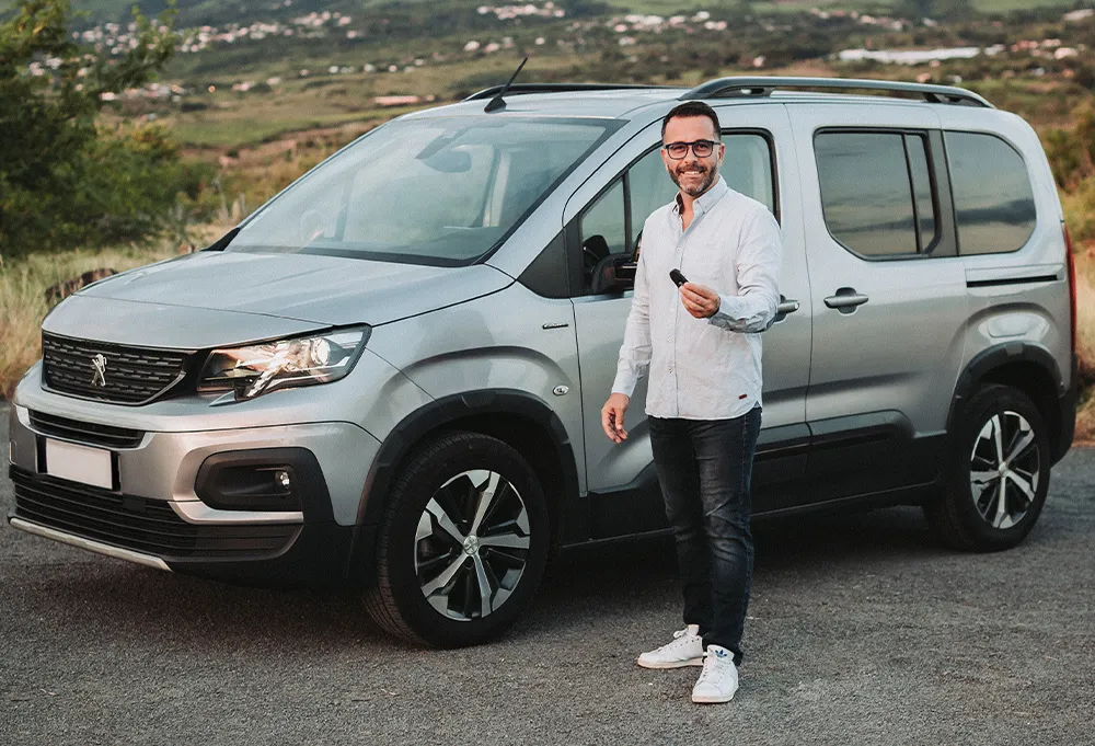 Gérant de Location Carrée avec les clés d'un Peugeot Rifter, voiture de location à La Réunion